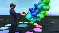 Person in virtual reality goggles interacting with protein model that is rendered as blue-green surface.